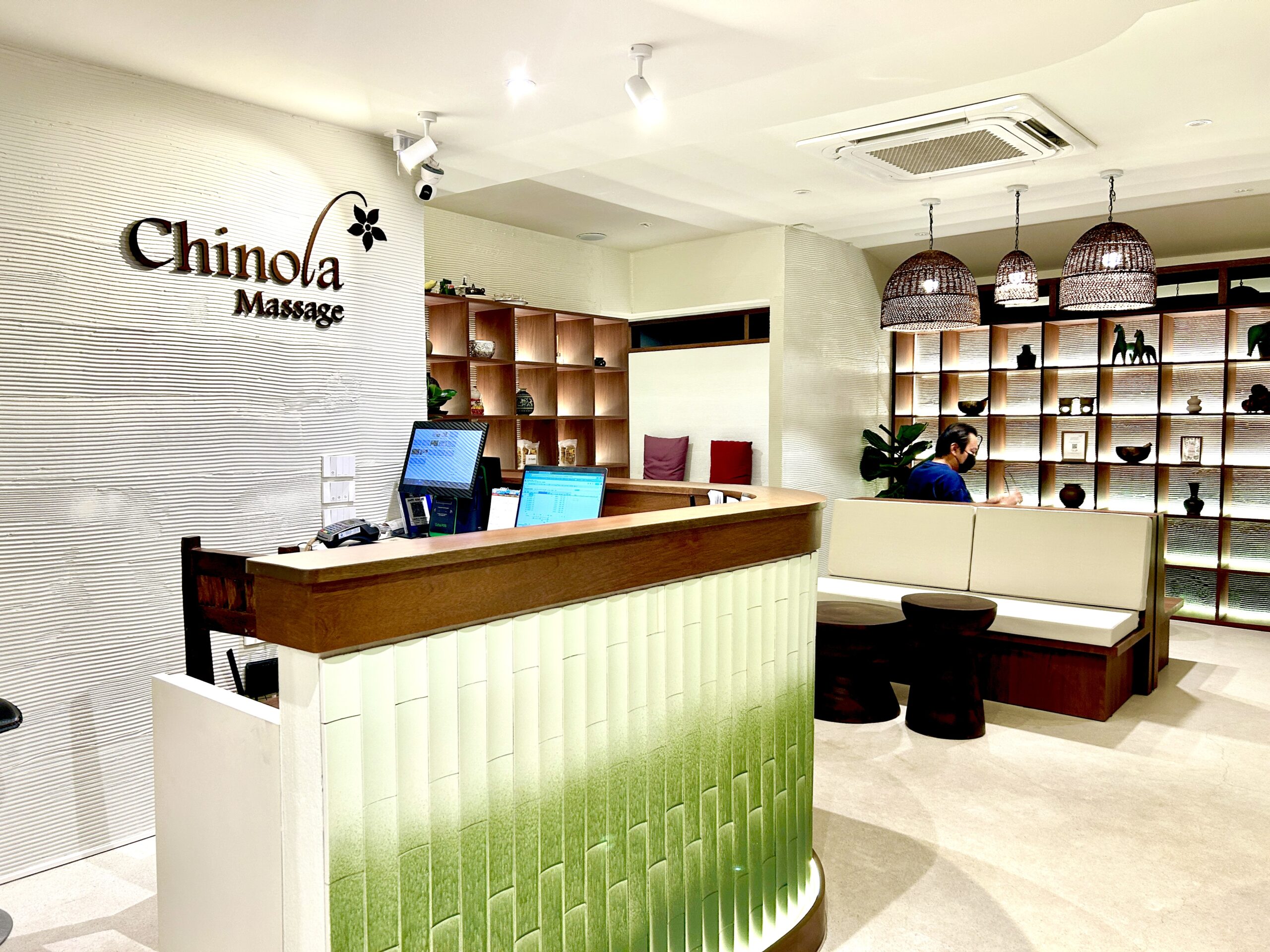 ล็อบบี้และเคาน์เตอร์ต้อนรับของร้าน Chinola Massage ตกแต่งสวยงามด้วยชั้นไม้และโคมไฟหวาย