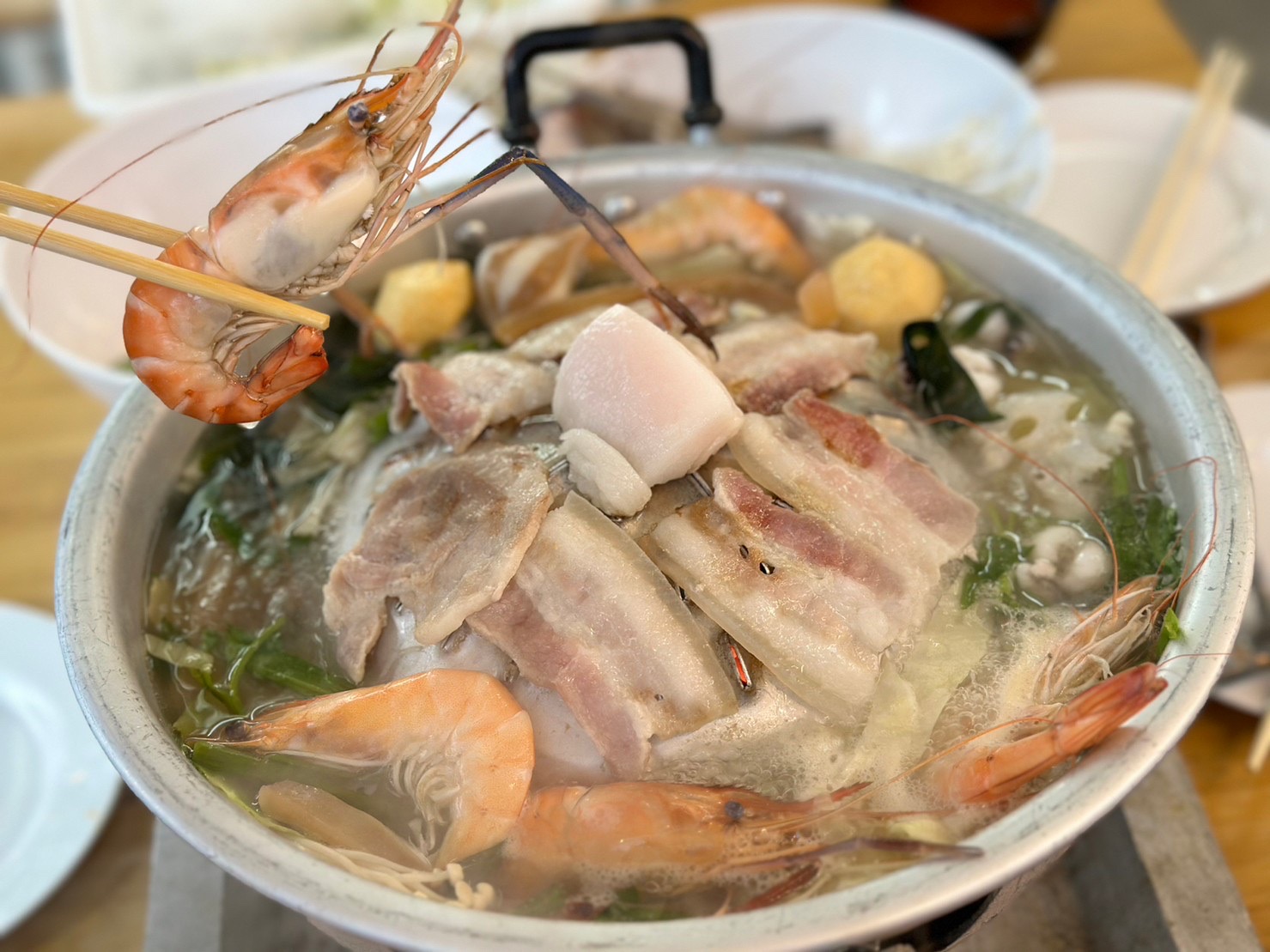 หม้อไฟทะเลรวมมิตรกับกุ้งสด เนื้อหมูสามชั้น ลูกชิ้น และผักในน้ำซุปร้อนๆ จับกุ้งด้วยตะเกียบ