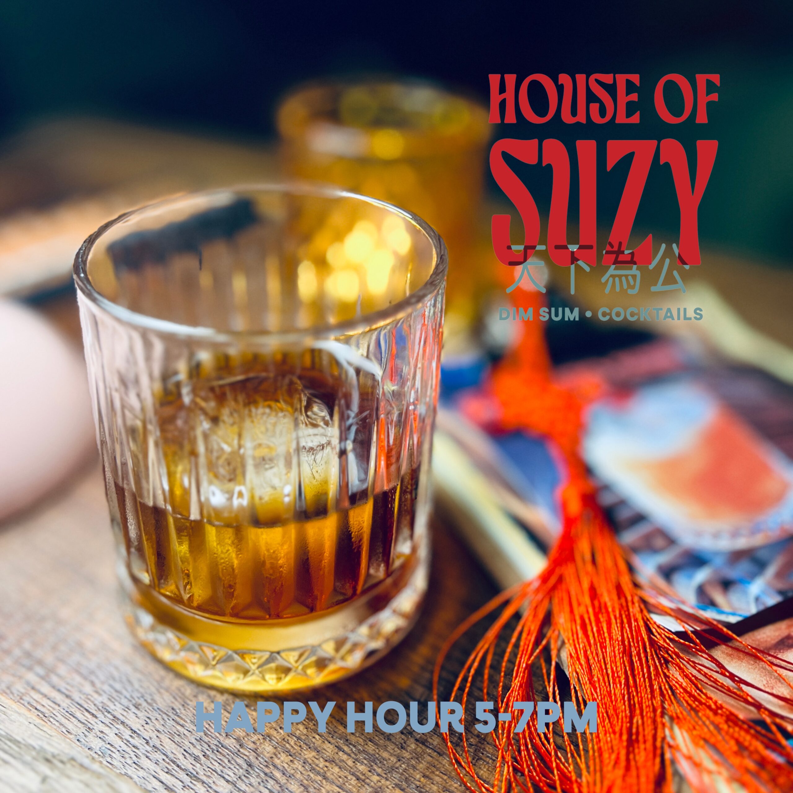 แก้ววิสกี้คริสตัลบนโต๊ะไม้ที่ร้าน House of Suzy ร้านติ่มซำและค็อกเทล พร้อมพู่ประดับสีแดงและป้ายโปรโมชัน Happy Hour 5-7PM
