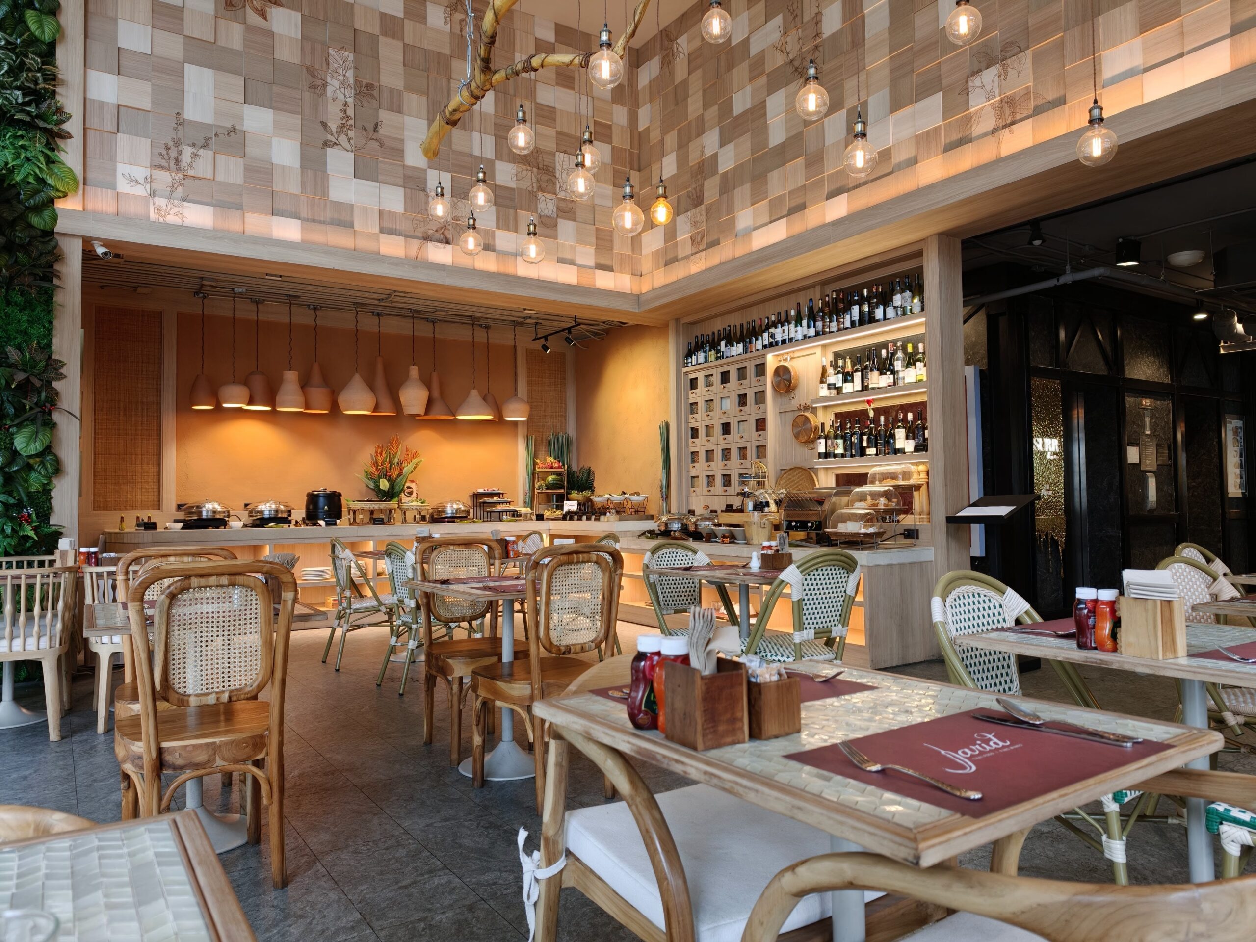 ภายในร้านอาหารตกแต่งด้วยไม้โทนสีอบอุ่น มีเพดานลายตารางไม้ โคมไฟแขวนสวยงาม บาร์ไวน์ และโต๊ะเก้าอี้ไม้สไตล์วินเทจ