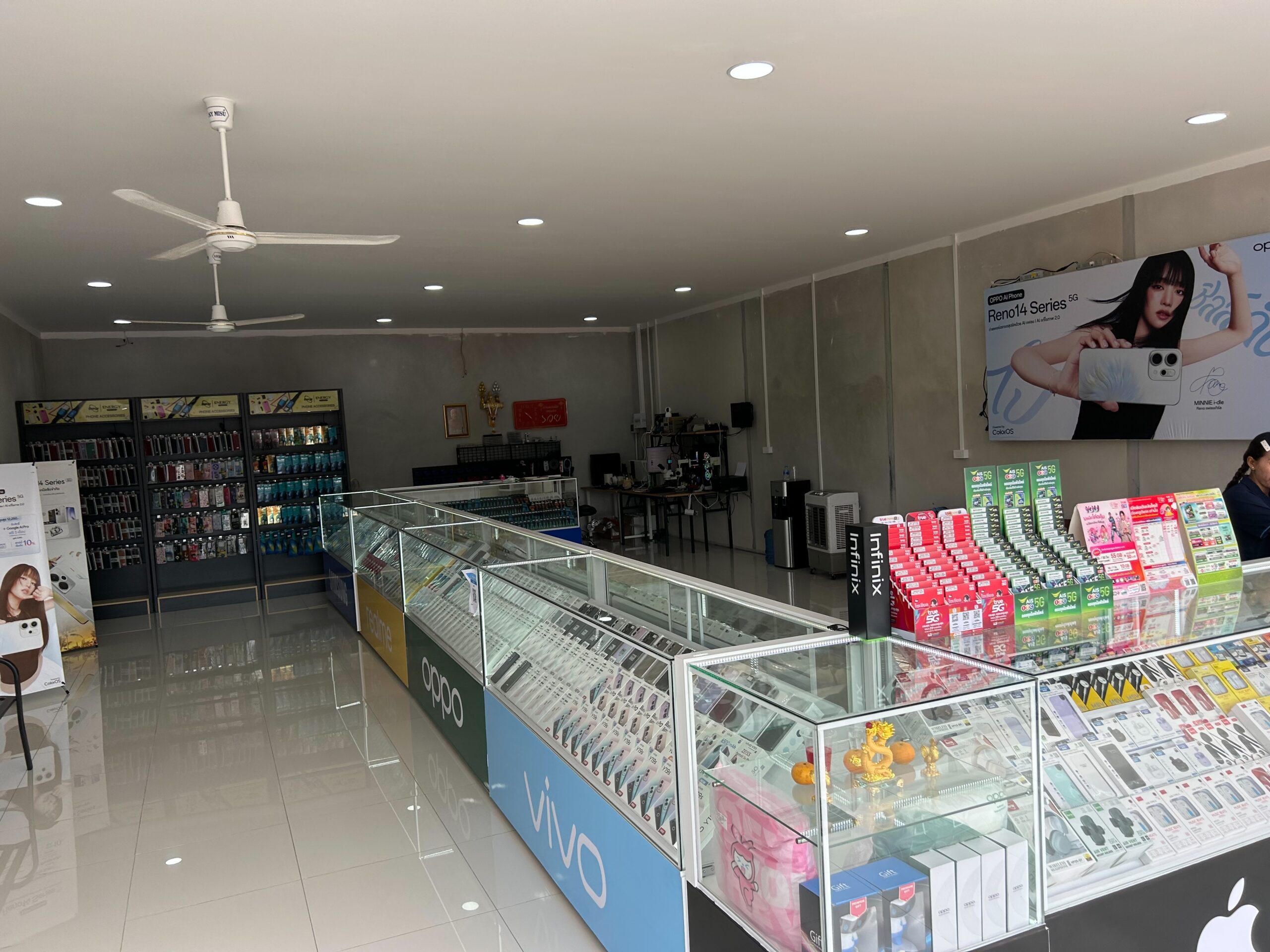 ภายในร้านขายโทรศัพท์มือถือที่มีตู้โชว์สินค้าแบรนด์ OPPO, Vivo, Infinix พร้อมอุปกรณ์เสริมและเคสมือถือ