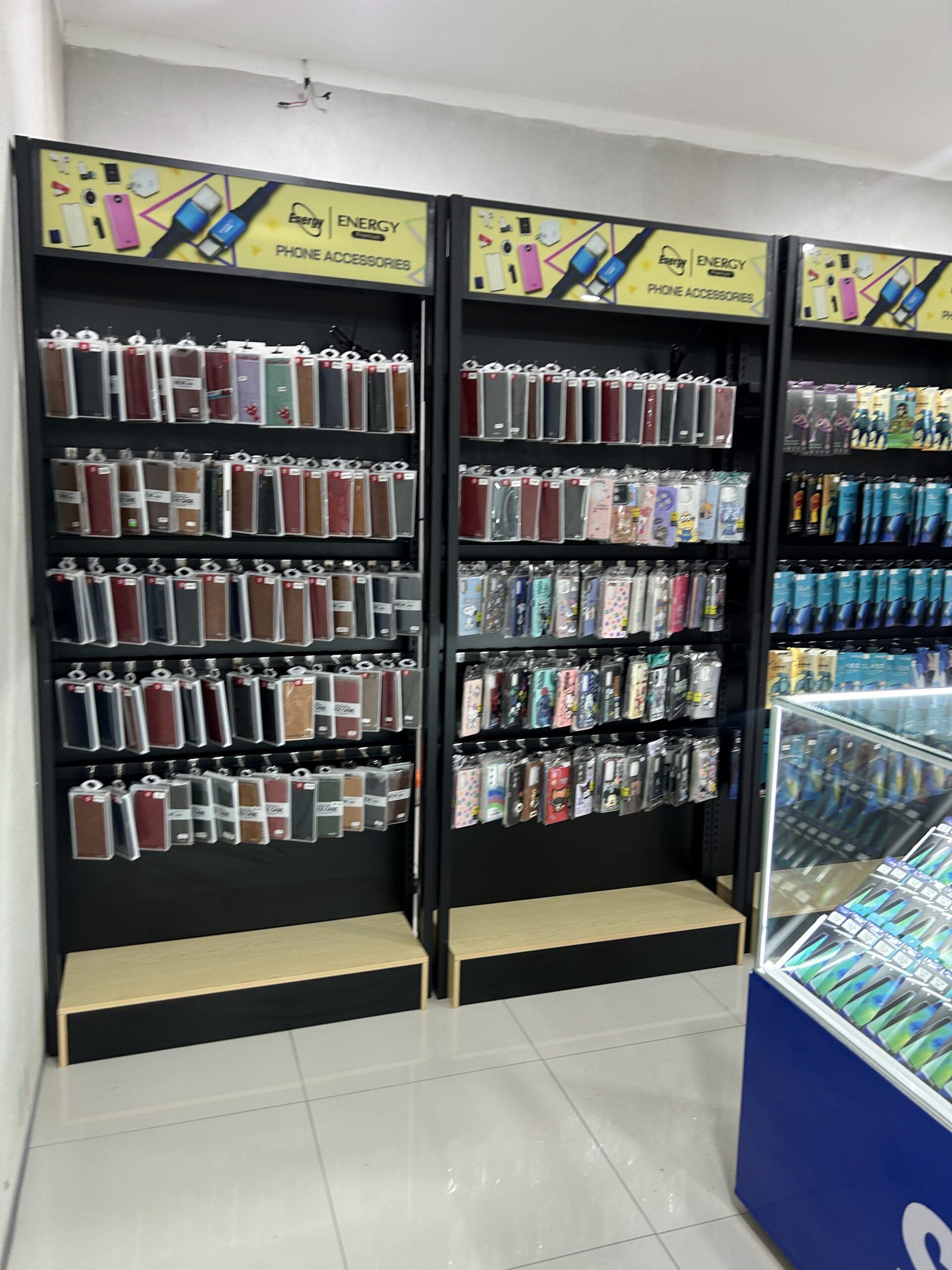 ชั้นวางแสดงเคสโทรศัพท์และอุปกรณ์เสริมมือถือหลากหลายแบบในร้าน Energy Phone Accessories