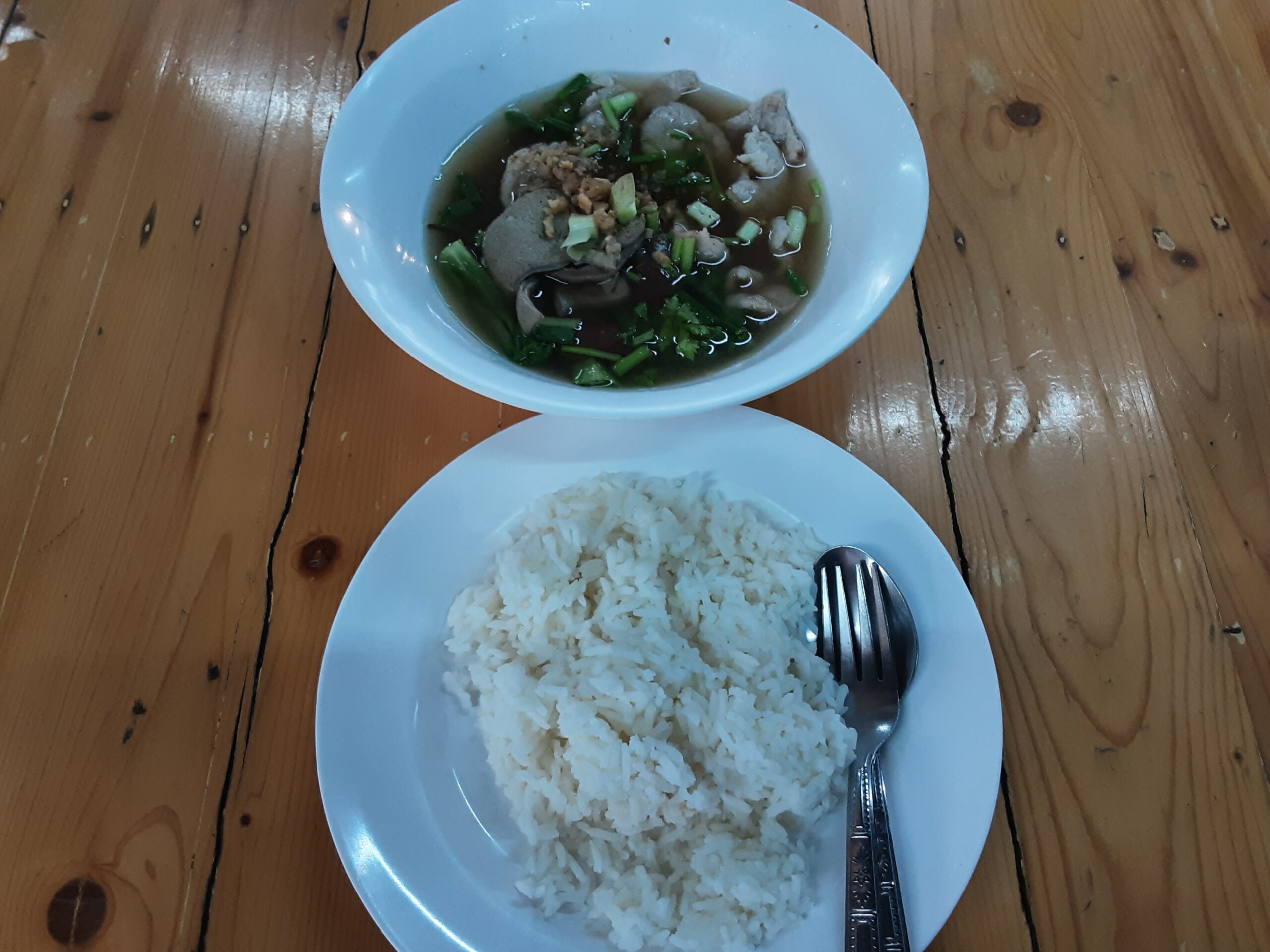 ข้าวสวยพร้อมแกงจืดลูกชิ้นหมูสับใส่ผักบนโต๊ะไม้