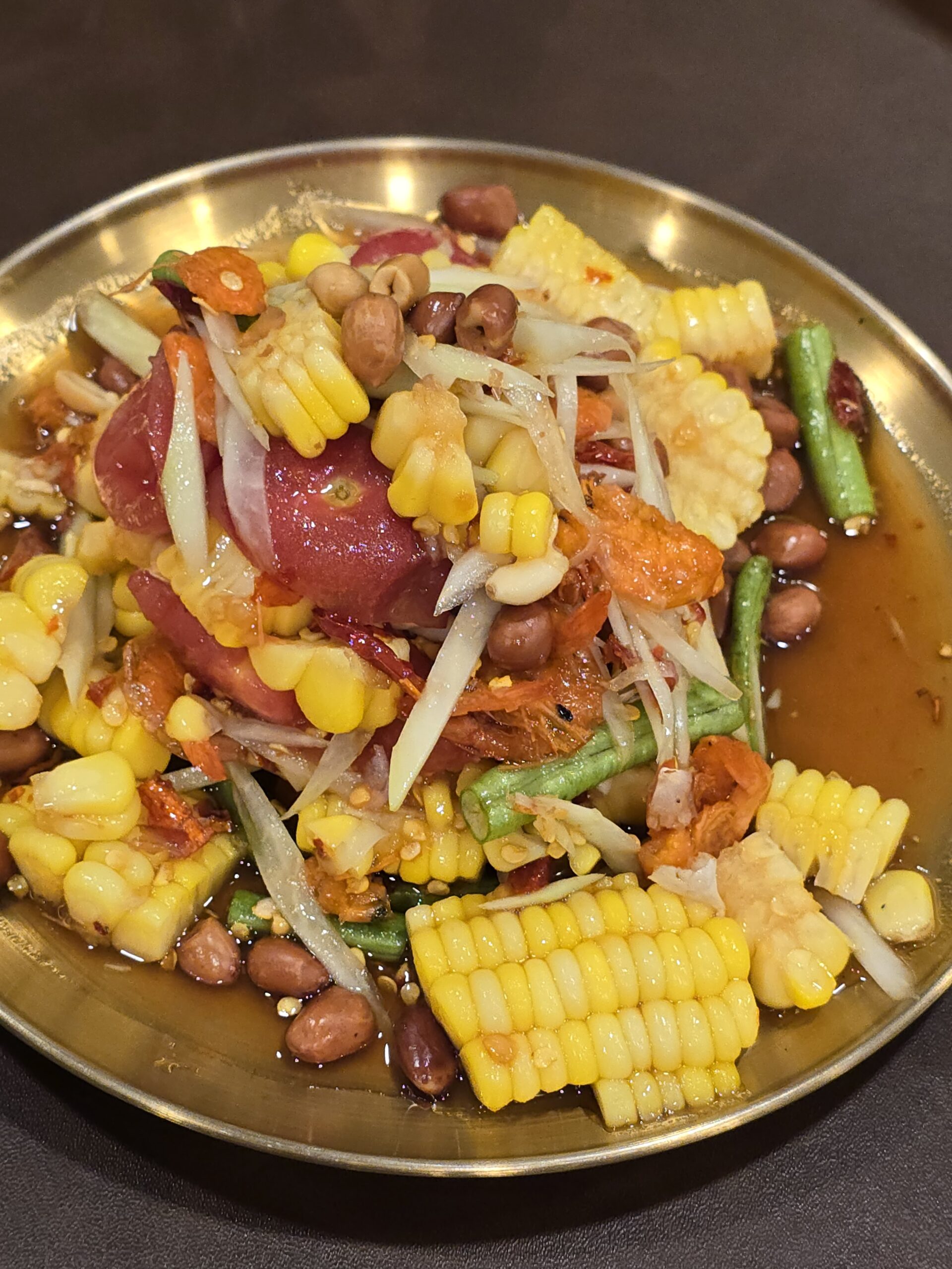 ส้มตำข้าวโพดถั่วลิสงกุ้งแห้งบนจานทองเหลือง เมนูอาหารอีสานรสจัด