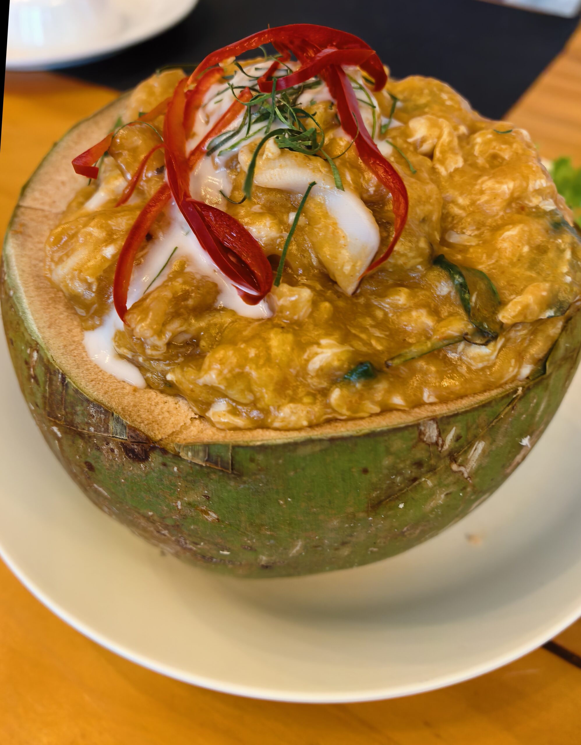 ห่อหมกทะเลเสิร์ฟในลูกมะพร้าวสด ราดกะทิ โรยพริกแดงซอยและใบมะกรูด