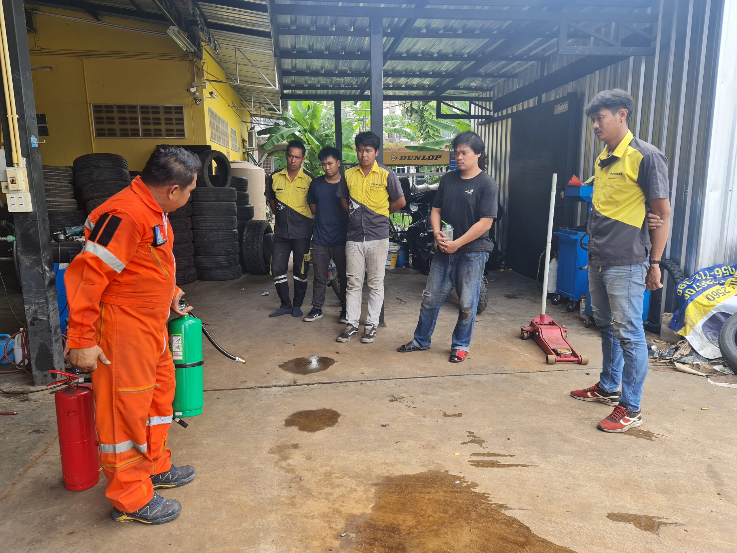 การฝึกอบรมดับเพลิงในร้านยางรถยนต์ โดยเจ้าหน้าที่กู้ภัยสาธิตการใช้ถังดับเพลิงให้พนักงานดู