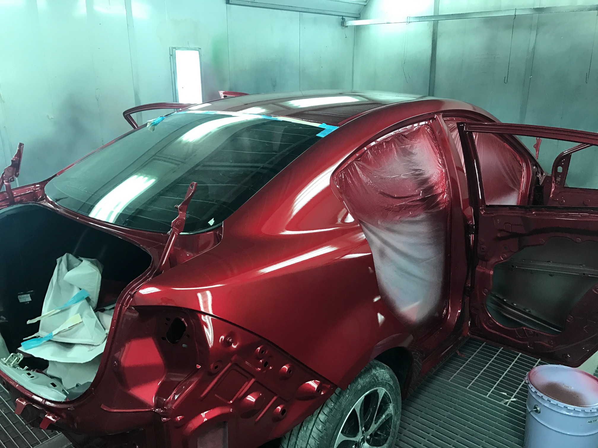 รถยนต์สีแดงกำลังถูกพ่นสีในห้องพ่นสีรถยนต์