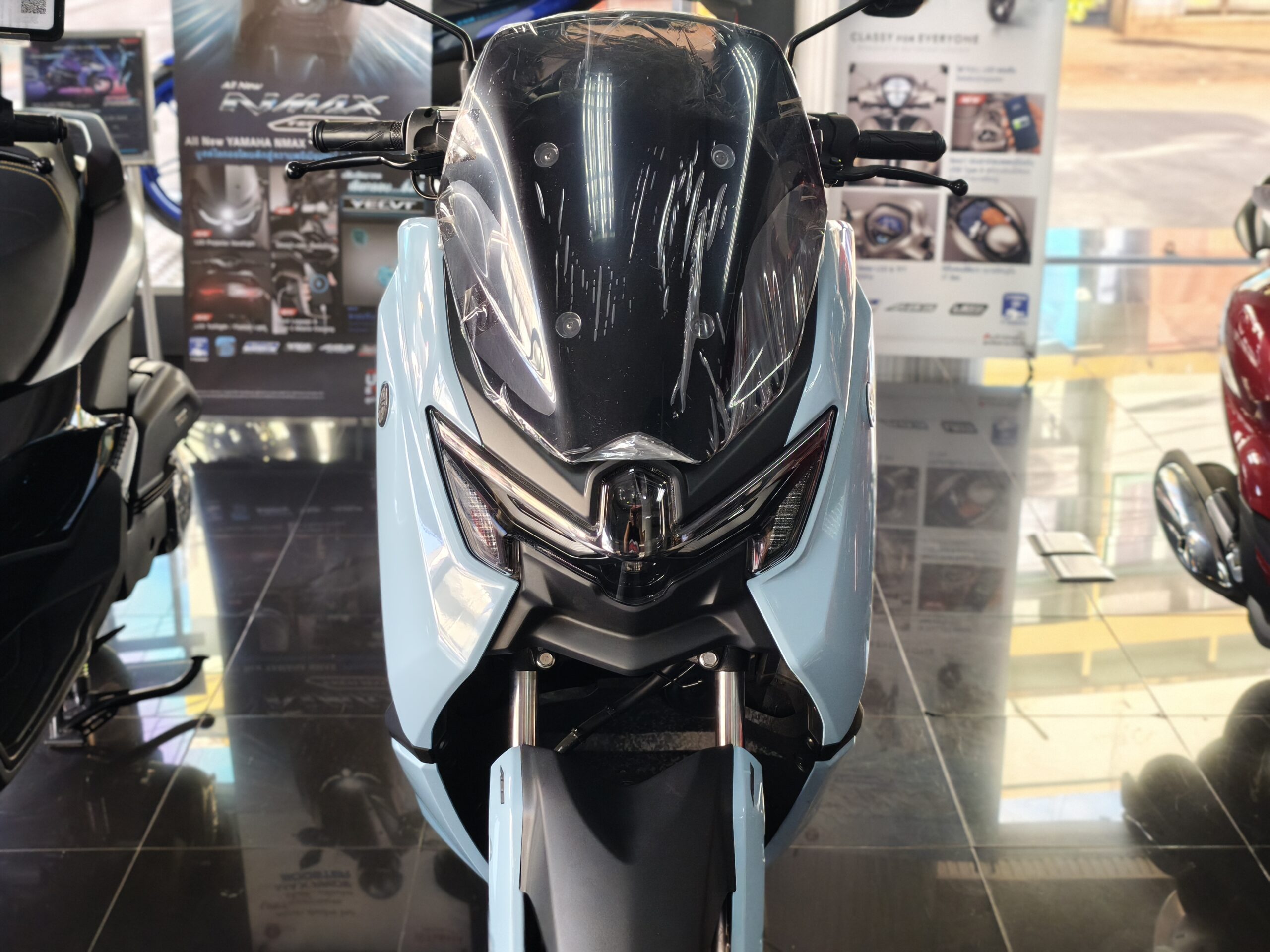 รถมอเตอร์ไซค์ยามาฮ่า NMAX สีฟ้าอ่อนจอดโชว์ในโชว์รูม มองจากด้านหน้า