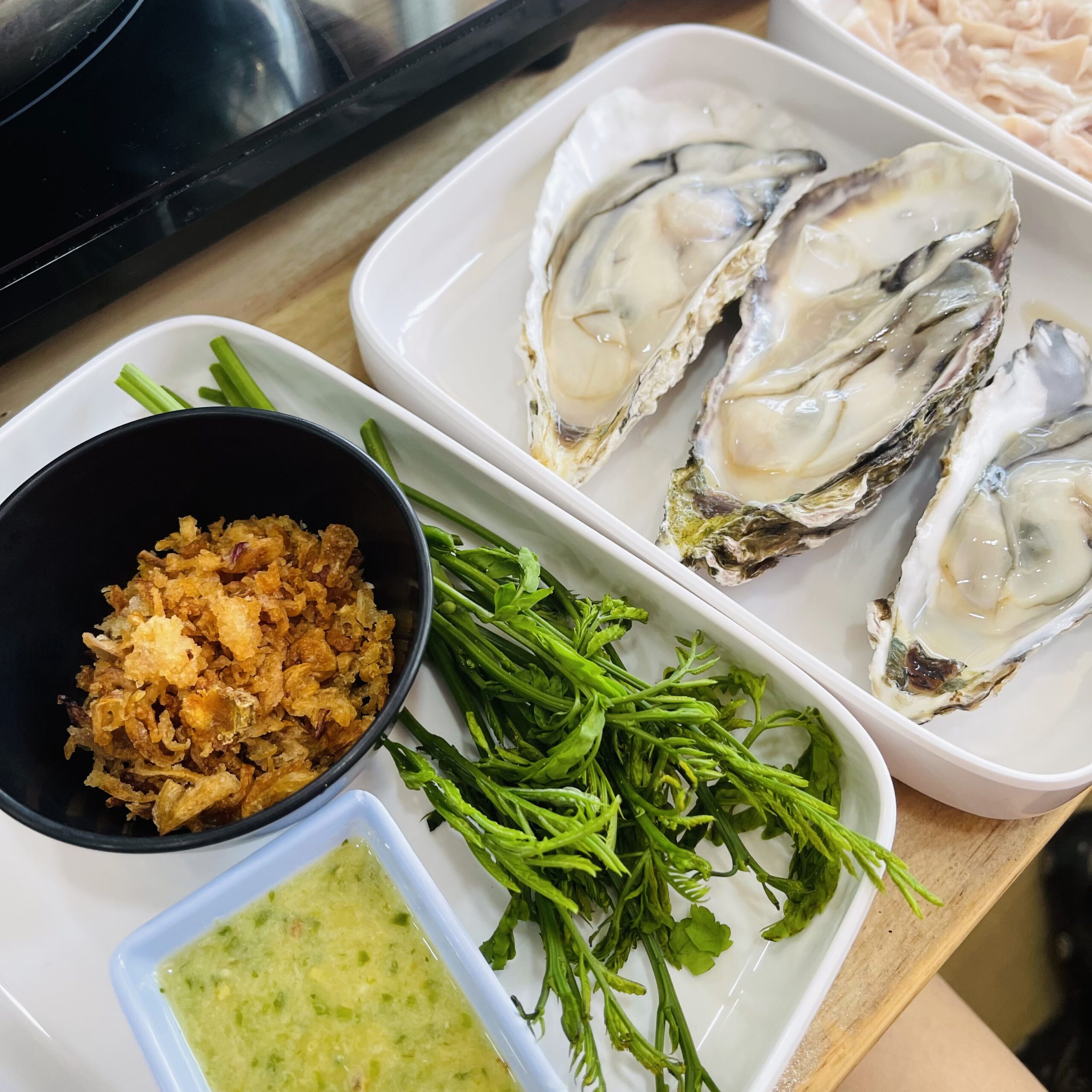 หอยนางรมสดบนจานพร้อมผักสด กากหมู น้ำจิ้มซีฟู้ด และเนื้อหมูสไลด์สำหรับชาบู