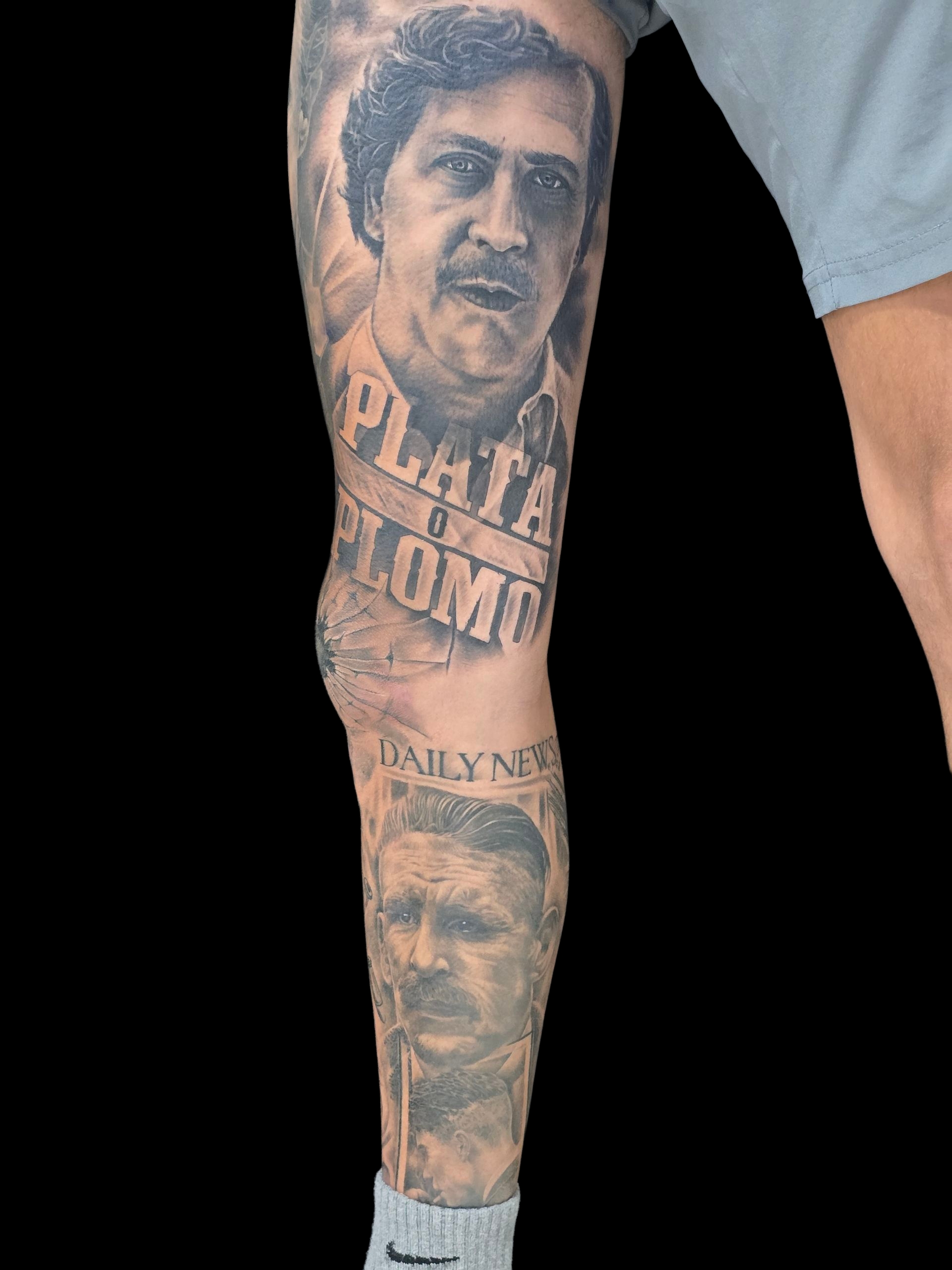 รอยสักขาเต็มขาลายเหมือนจริงขาวดำรูปใบหน้าชายพร้อมข้อความ Plata o Plomo และ Daily News