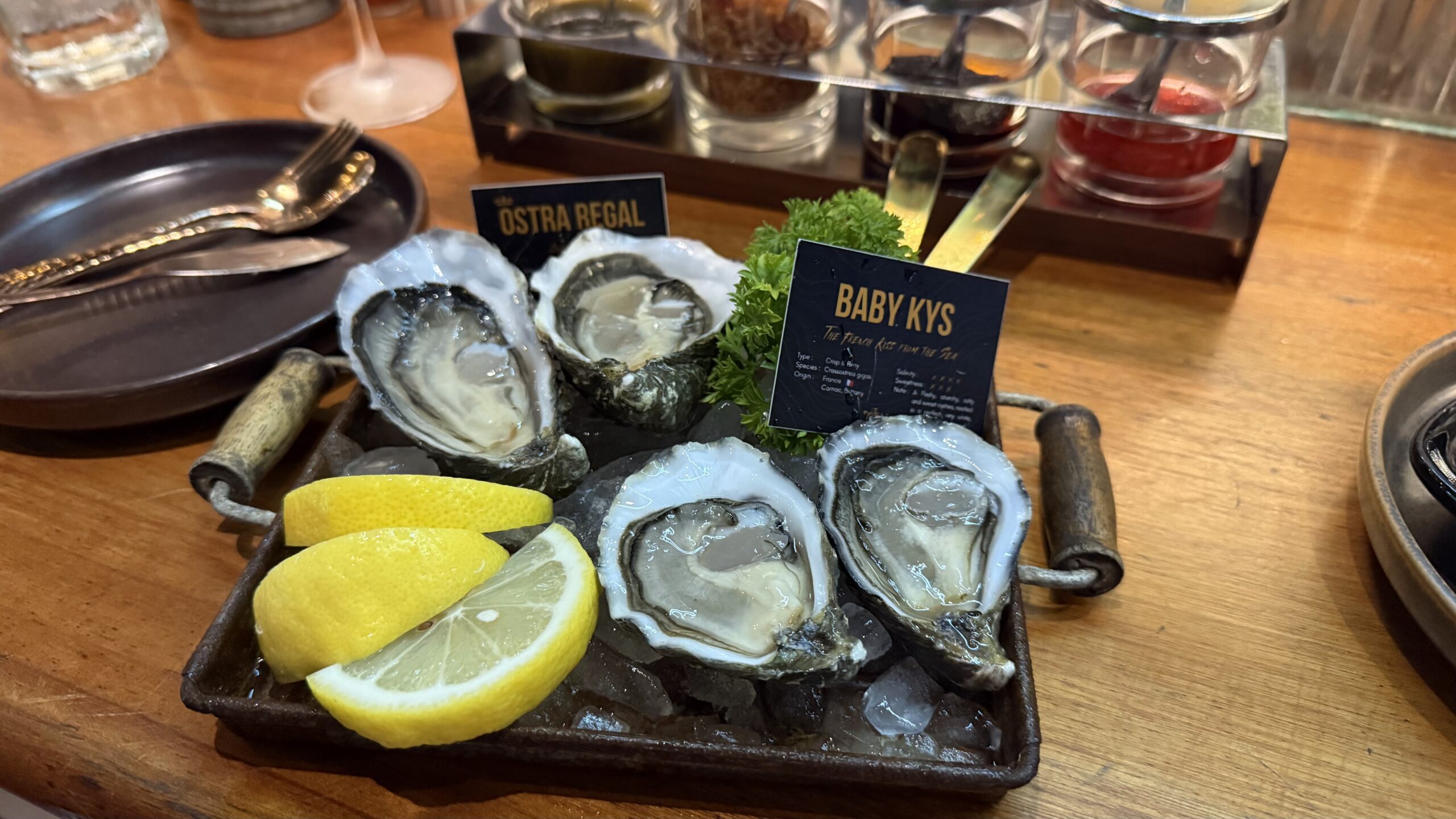 จานหอยนางรมสดบนน้ำแข็ง Baby Kys พร้อมเลมอนเสิร์ฟบนถาดเหล็กที่ร้าน Ostra Regal