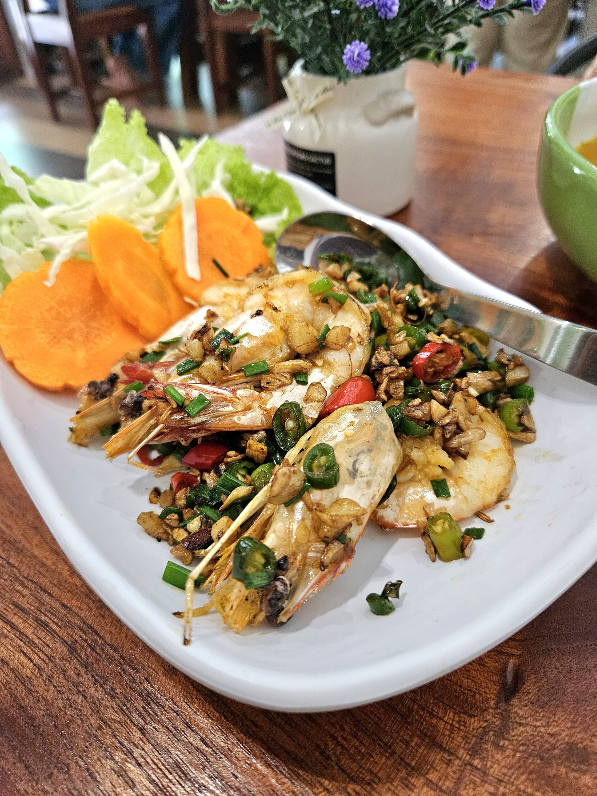 กุ้งทอดกระเทียมพริกไทยเสิร์ฟบนจานขาวพร้อมผักสดแครอทและผักกาดหอม