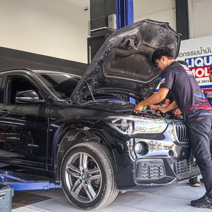 ช่างซ่อมรถกำลังตรวจเช็คเครื่องยนต์รถ BMW สีดำในอู่ซ่อมรถ