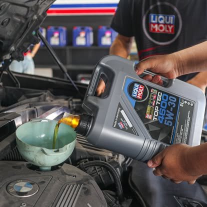 ช่างกำลังเทน้ำมันเครื่อง Liqui Moly Top Tec 4600 5W-30 ลงในเครื่องยนต์รถยนต์ BMW ที่ศูนย์บริการ