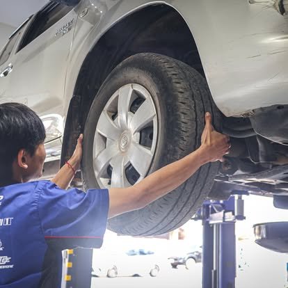 ช่างซ่อมรถกำลังเปลี่ยนยางรถยนต์ที่ยกขึ้นบนลิฟต์ในอู่ซ่อมรถ