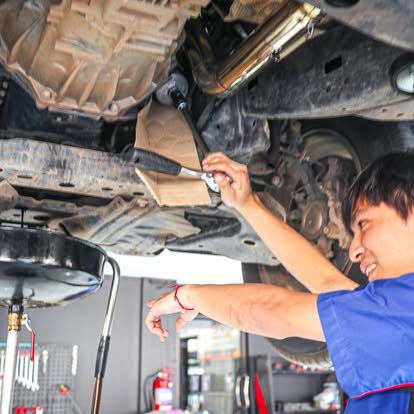 ช่างหญิงกำลังซ่อมใต้ท้องรถยนต์ในอู่