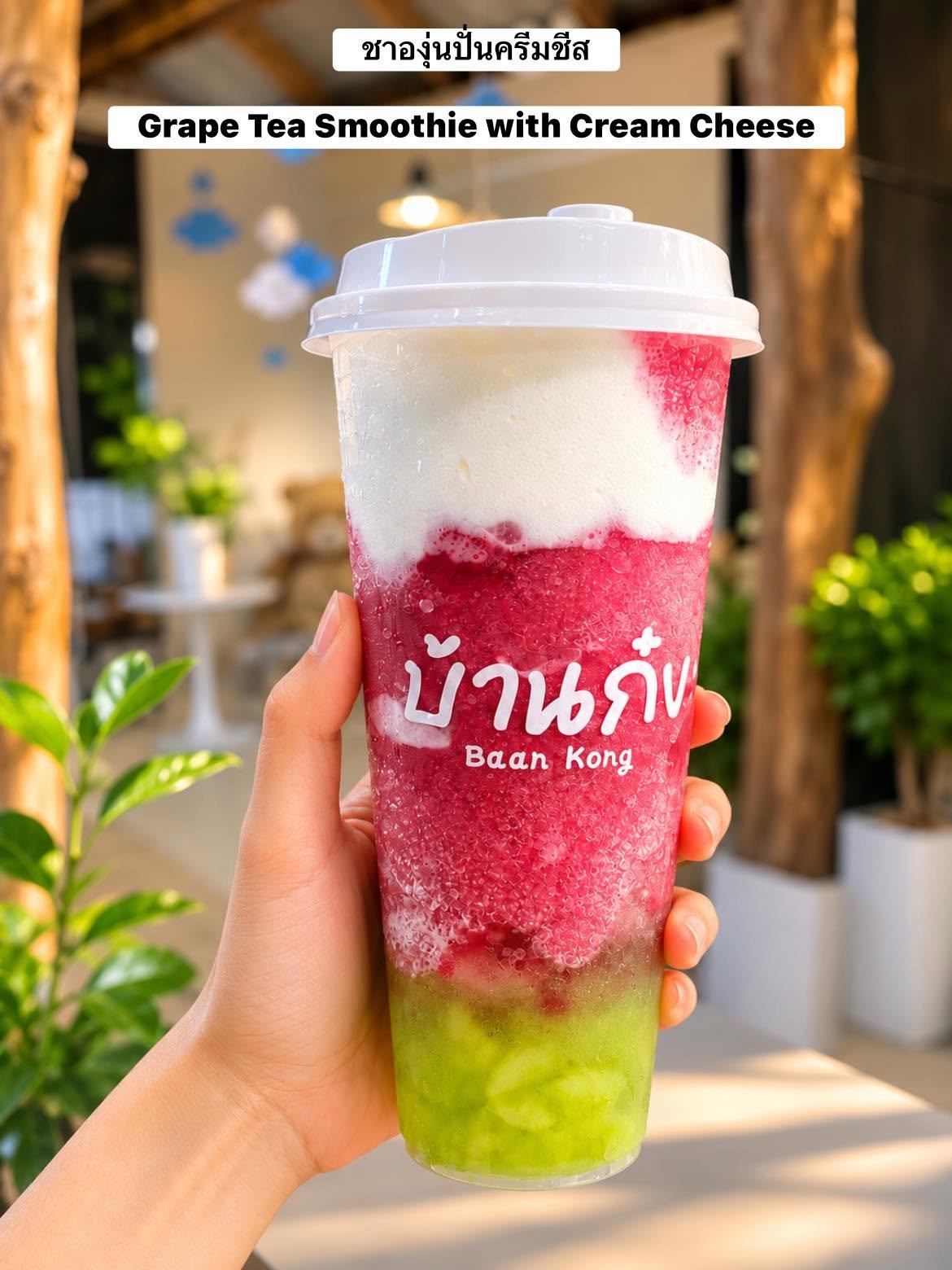 ชาองุ่นปั่นครีมชีสจากร้านบ้านกง เครื่องดื่มสีชมพูสดใสกับครีมชีสด้านบนและชั้นสีเขียวด้านล่างในแก้วใหญ่