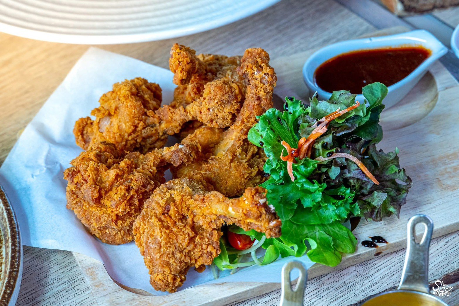 ไก่ทอดกรอบเสิร์ฟบนเขียงไม้พร้อมผักสลัดสดและซอสจิ้มรสเข้มข้น