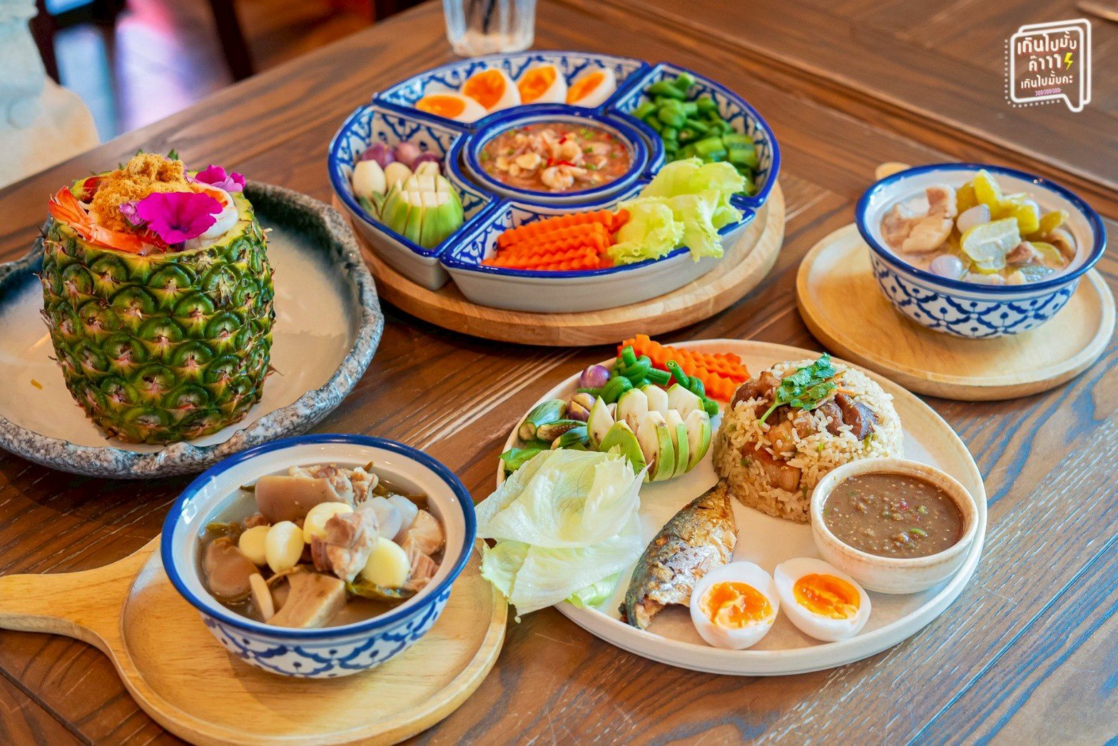 สำรับอาหารไทยโบราณบนโต๊ะไม้ ประกอบด้วยข้าวผัดปลาทู น้ำพริกกะปิผักสด เสิร์ฟในจานเบญจรงค์ ข้าวอบสับปะรด แกงจืดและไข่ต้มยางมะตูม
