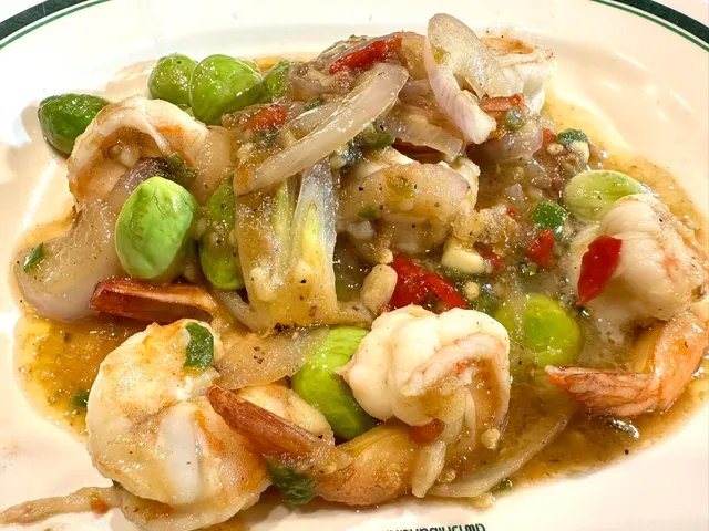 กุ้งผัดสะตอพริกแกง จานอาหารไทยใต้ กุ้งตัวโตผัดกับสะตอเขียว หอมแดง พริกแดง ในจานสีขาว