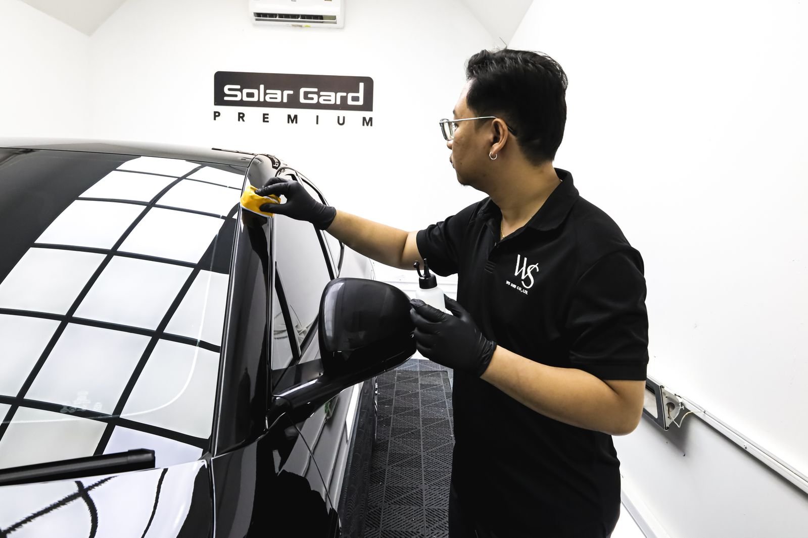 ช่างติดฟิล์มกรองแสง Solar Gard Premium กำลังติดฟิล์มกระจกรถยนต์สีดำในห้องปฏิบัติงาน
